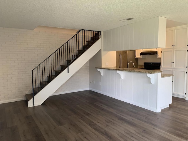 9847 Mission Vega Rd Unit 3, Santee, CA 92071 - kitchen featuring brick wall, freestanding refrigerator, dark wood finished floors, a textured ceiling, and a breakfast bar