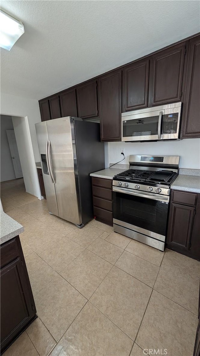 1679 Stoneside Dr, Hemet, CA 92545 - kitchen featuring stainless steel appliances, light countertops, dark brown cabinets, light tile patterned flooring, and a textured ceiling