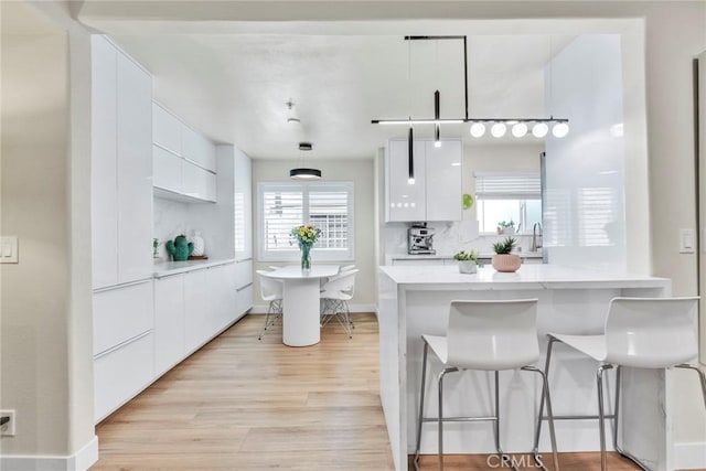 166 Alta St Unit B, Arcadia, CA 91006 - kitchen with modern cabinets, white cabinetry, a kitchen bar, light wood-style floors, and hanging light fixtures