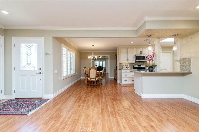 3238 San Amadeo Unit C, Laguna Woods, CA 92637 - kitchen featuring stainless steel appliances, a chandelier, light wood finished floors, decorative backsplash, and pendant lighting