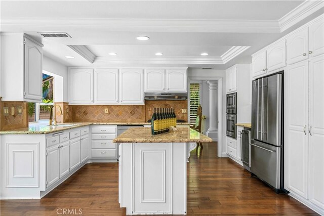 29212 Dean St, Laguna Niguel, CA 92677 - kitchen with appliances with stainless steel finishes, under cabinet range hood, light stone countertops, white cabinets, and crown molding