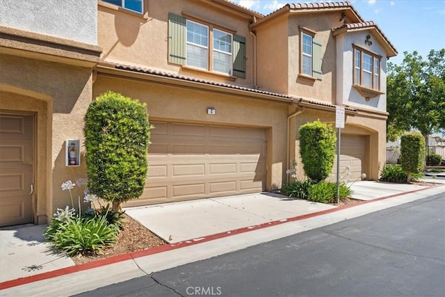 26327 Iris Ave Unit C, Moreno Valley, CA 92555 - mediterranean / spanish house featuring an attached garage, stucco siding, driveway, and a tiled roof