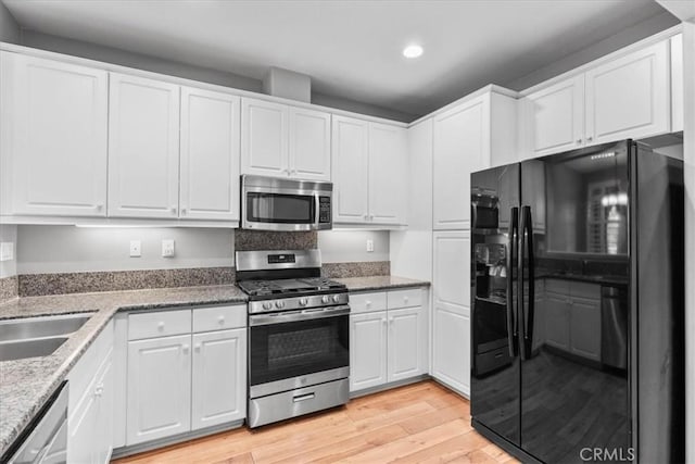 26327 Iris Ave Unit C, Moreno Valley, CA 92555 - kitchen with appliances with stainless steel finishes, recessed lighting, white cabinets, light wood finished floors, and light stone counters