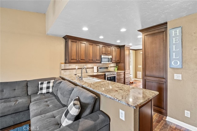 3197 Bexfield Ct, Riverside, CA 92503 - kitchen with appliances with stainless steel finishes, dark wood-type flooring, light stone counters, recessed lighting, and tasteful backsplash