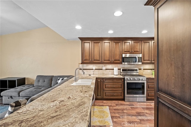 3197 Bexfield Ct, Riverside, CA 92503 - kitchen featuring appliances with stainless steel finishes, wood finished floors, decorative backsplash, light stone counters, and recessed lighting