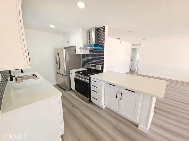 7927 Chastain Pl, Reseda, CA 91335 - kitchen featuring stainless steel appliances, wall chimney exhaust hood, light wood-style floors, white cabinetry, and backsplash