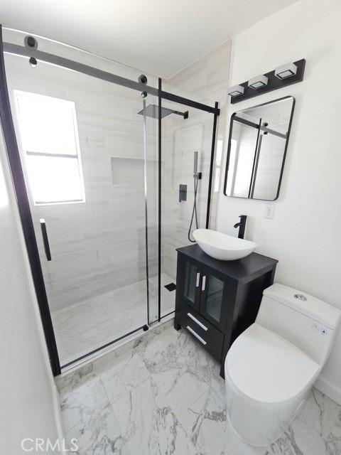7927 Chastain Pl, Reseda, CA 91335 - bathroom featuring marble look tiles, vanity, and a stall shower