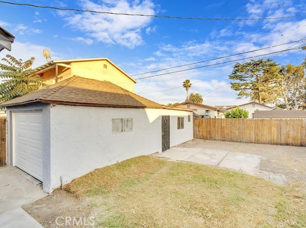 1438 W 69th St, Los Angeles, CA 90047 - rear view of property with stucco siding, a shingled roof, and a garage