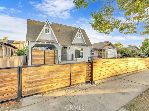 1438 W 69th St, Los Angeles, CA 90047 - view of front facade featuring stucco siding, a fenced front yard, a gate, and a shingled roof