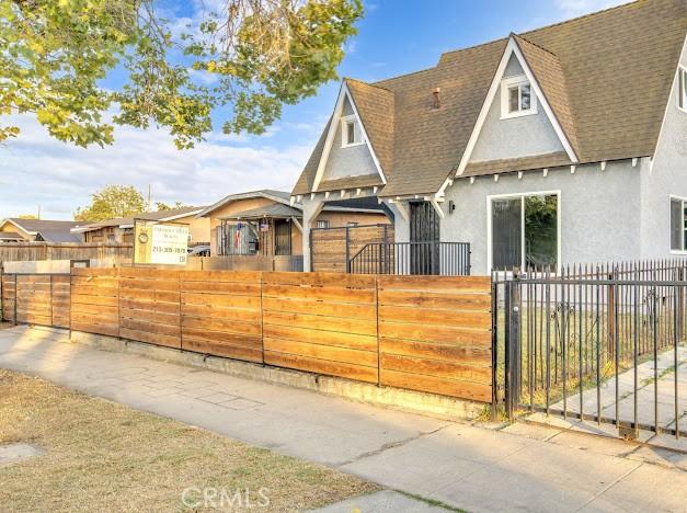 1438 W 69th St, Los Angeles, CA 90047 - view of front of house with stucco siding, roof with shingles, a fenced front yard, and a gate
