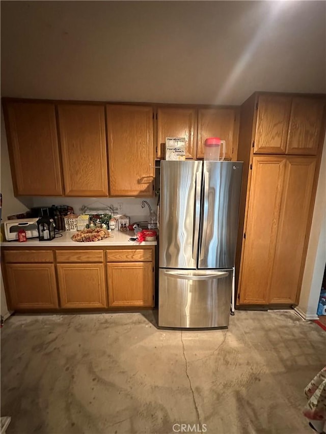 15654 Enfield Dr, Victorville, CA 92394 - kitchen featuring freestanding refrigerator, light countertops, brown cabinets, and unfinished concrete floors