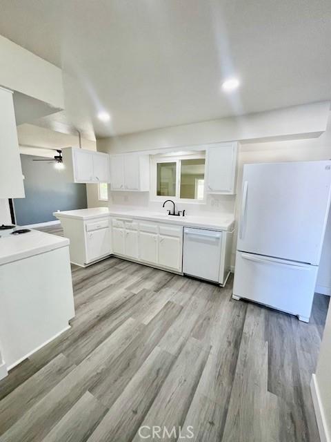 28838 Snead Dr, Menifee, CA 92586 - kitchen featuring white appliances, white cabinets, light wood-style floors, and light countertops