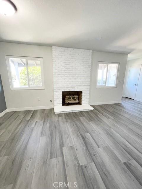 28838 Snead Dr, Menifee, CA 92586 - unfurnished living room with a brick fireplace, healthy amount of natural light, and wood finished floors