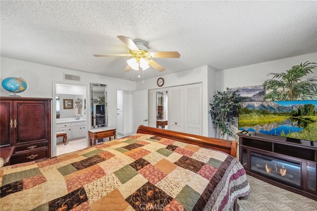 621 Shasta Way, Hemet, CA 92543 - bedroom featuring a closet, a textured ceiling, ensuite bath, ceiling fan, and a glass covered fireplace