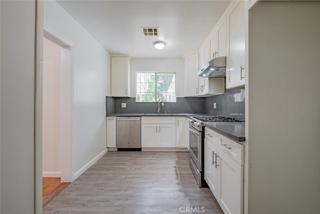 16908 Los Alimos St, Granada Hills, CA 91344 - kitchen with stainless steel appliances, under cabinet range hood, light wood finished floors, decorative backsplash, and dark countertops
