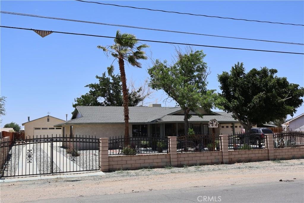 12386 Pawnee Rd, Apple Valley, CA 92308 - view of front of house with a fenced front yard, a garage, a shingled roof, and driveway