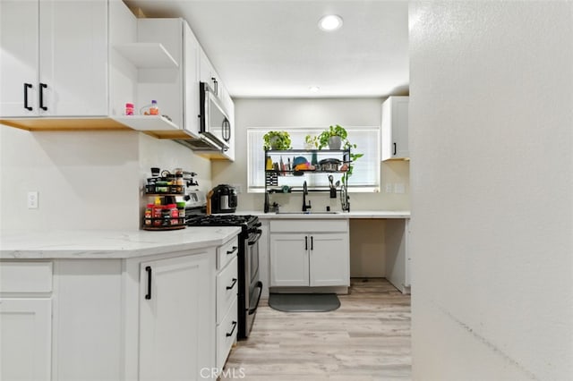 29246 Radio Rd, Barstow, CA 92311 - kitchen with appliances with stainless steel finishes, open shelves, light wood-style flooring, light stone counters, and white cabinets