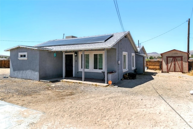 29246 Radio Rd, Barstow, CA 92311 - view of front of home with solar panels, a shed, stucco siding, covered porch, and roof with shingles