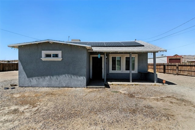 29246 Radio Rd, Barstow, CA 92311 - view of front of house with stucco siding, a fenced backyard, roof mounted solar panels, and a patio area