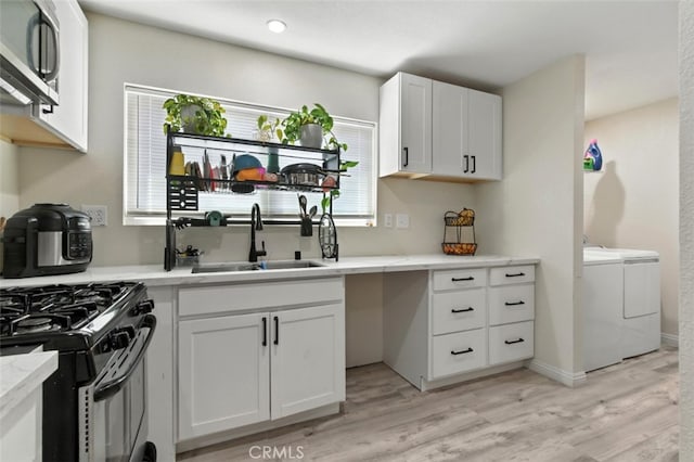 29246 Radio Rd, Barstow, CA 92311 - kitchen with washer and clothes dryer, stainless steel microwave, light wood-style flooring, white cabinets, and gas stove