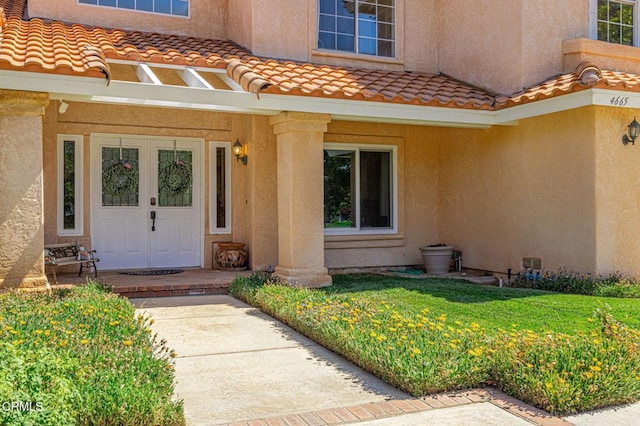 4665 Northridge Dr, Palmdale, CA 93551 - doorway to property with stucco siding, a tiled roof, and a lawn