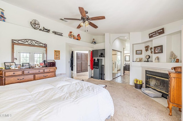 4665 Northridge Dr, Palmdale, CA 93551 - bedroom with arched walkways, light carpet, a tile fireplace, light tile patterned floors, and a ceiling fan