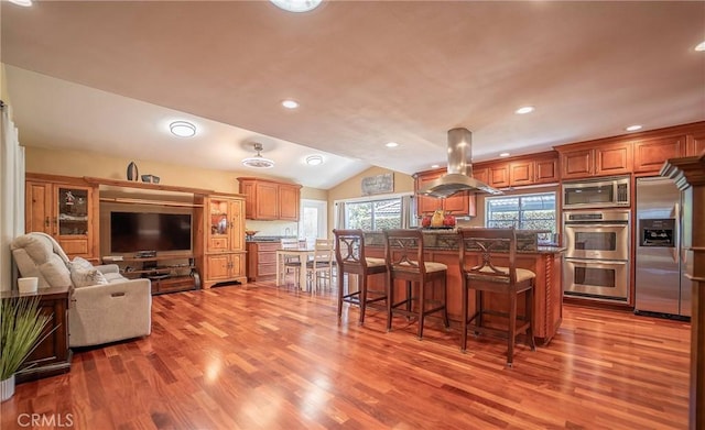 25532 Maximus St, Mission Viejo, CA 92675 - kitchen featuring island range hood, stainless steel appliances, a breakfast bar area, wood finished floors, and lofted ceiling