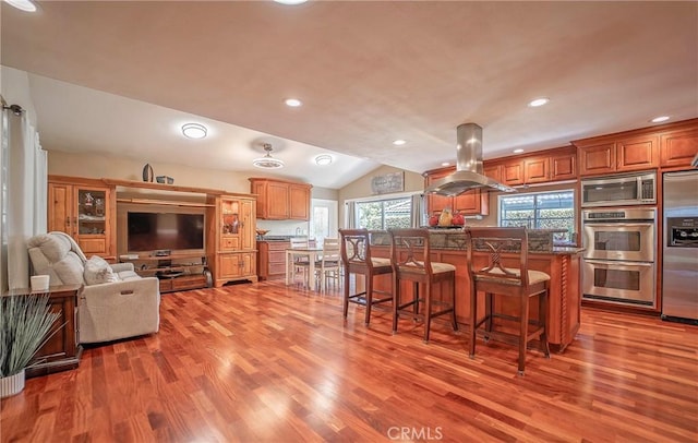 25532 Maximus St, Mission Viejo, CA 92675 - kitchen featuring island range hood, appliances with stainless steel finishes, wood finished floors, a kitchen bar, and vaulted ceiling
