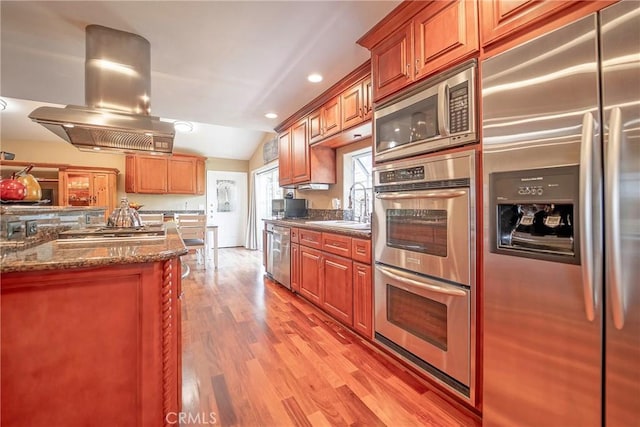 25532 Maximus St, Mission Viejo, CA 92675 - kitchen with stainless steel appliances, island range hood, light wood-style flooring, dark stone counters, and vaulted ceiling