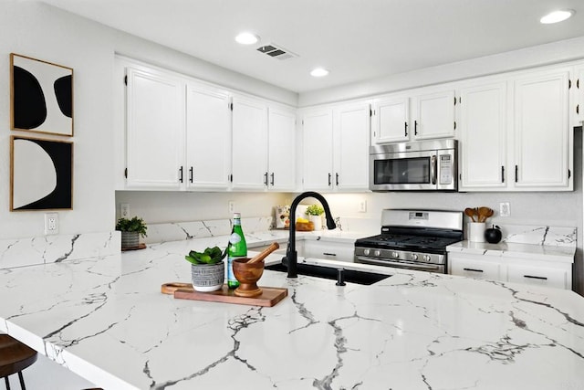 1250 Pinnacle Peak, Chula Vista, CA 91915 - kitchen featuring stainless steel appliances, light stone counters, white cabinets, recessed lighting, and a peninsula
