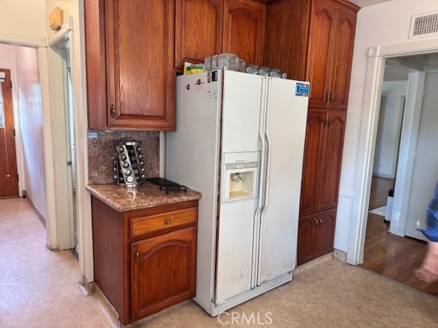 15945 Lashburn St, Whittier, CA 90603 - kitchen featuring white refrigerator with ice dispenser, dark stone counters, brown cabinets, and tasteful backsplash