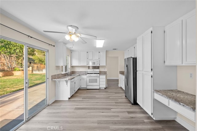 31772 Ridgeview Dr, Lake Elsinore, CA 92532 - kitchen with white appliances, white cabinets, light stone countertops, and a ceiling fan