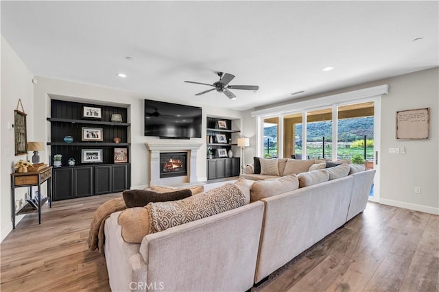 33303 Barmetta Ln, Temecula, CA 92592 - living room with light wood finished floors, a ceiling fan, a glass covered fireplace, built in features, and recessed lighting