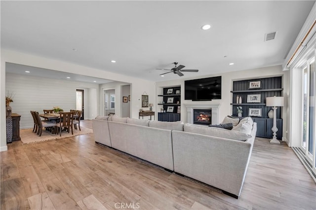 33303 Barmetta Ln, Temecula, CA 92592 - living area with ceiling fan, light wood-style flooring, a glass covered fireplace, recessed lighting, and built in features