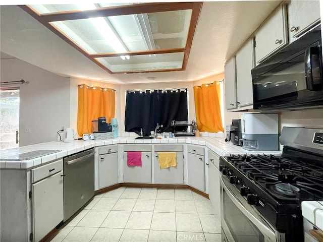 37543 Royal Ct, Palmdale, CA 93552 - kitchen featuring appliances with stainless steel finishes, a peninsula, light tile patterned floors, and tile counters