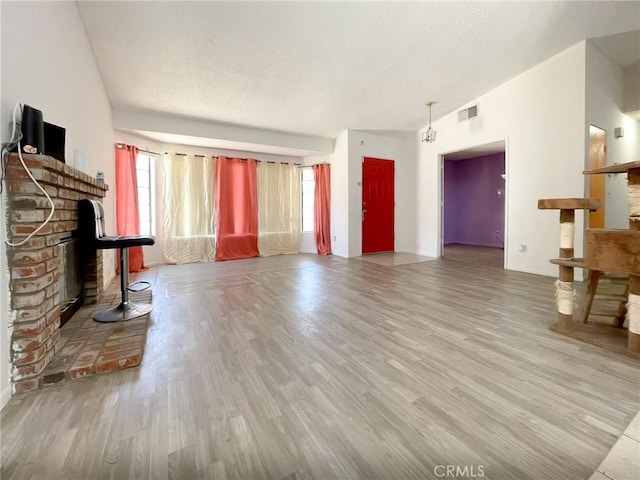 37543 Royal Ct, Palmdale, CA 93552 - unfurnished living room featuring wood finished floors, a textured ceiling, lofted ceiling, and a fireplace