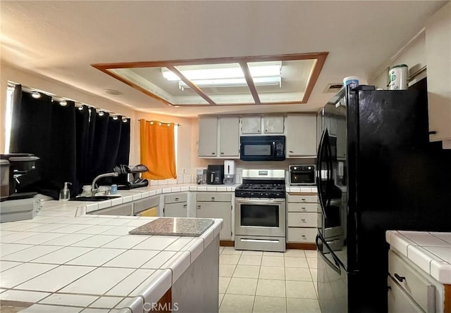37543 Royal Ct, Palmdale, CA 93552 - kitchen featuring black appliances, tile countertops, a tray ceiling, and light tile patterned floors