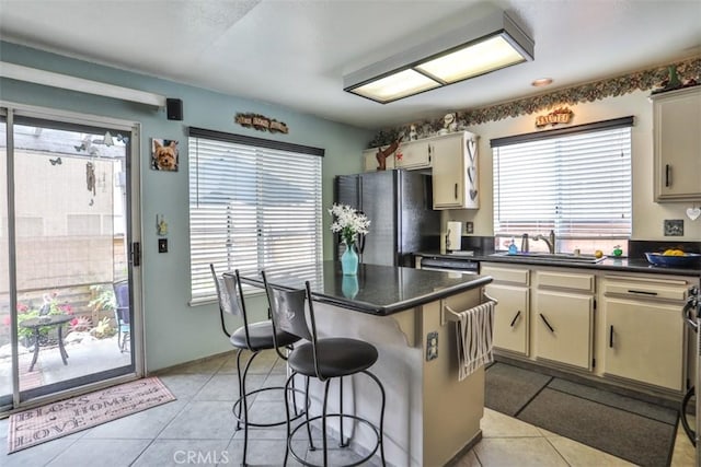 7331 Belpine Pl Unit 31, Rancho Cucamonga, CA 91730 - kitchen featuring freestanding refrigerator, dark countertops, a kitchen breakfast bar, light tile patterned flooring, and a center island