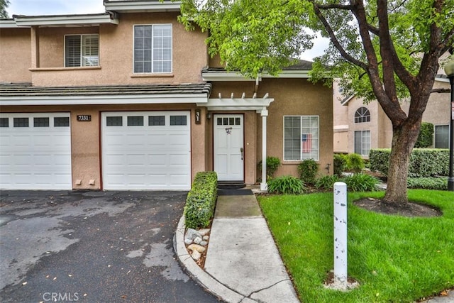 7331 Belpine Pl Unit 31, Rancho Cucamonga, CA 91730 - view of front of property featuring driveway, stucco siding, a garage, and a front lawn