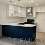16600 Seville Ave Unit F, Fontana, CA 92335 - kitchen featuring wall chimney range hood, stove, light countertops, hanging light fixtures, and recessed lighting