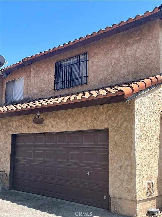 16600 Seville Ave Unit F, Fontana, CA 92335 - view of front of home featuring an attached garage, stucco siding, and a tile roof