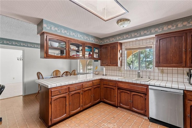 1529 Pomeroy Rd, Arroyo Grande, CA 93420 - kitchen featuring stainless steel dishwasher, a peninsula, a skylight, tasteful backsplash, and glass insert cabinets