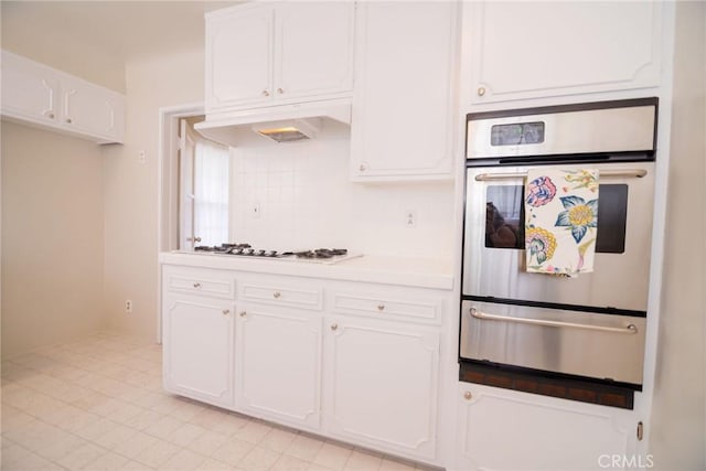 251 W 112th St, Los Angeles, CA 90061 - kitchen featuring a warming drawer, stainless steel oven, white cabinetry, light countertops, and tasteful backsplash