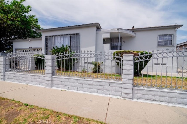 251 W 112th St, Los Angeles, CA 90061 - view of front of house with a fenced front yard, stucco siding, and an attached garage
