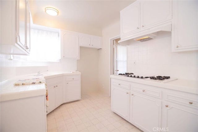 251 W 112th St, Los Angeles, CA 90061 - kitchen with white cabinets, decorative backsplash, tile counters, and white gas stovetop