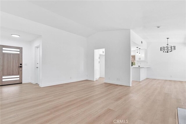 7720 Windsor Ave, Hesperia, CA 92345 - unfurnished living room featuring light wood-style flooring, a chandelier, and lofted ceiling
