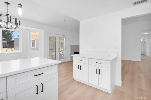 7720 Windsor Ave, Hesperia, CA 92345 - kitchen with a chandelier, light wood-style flooring, french doors, white cabinets, and decorative light fixtures