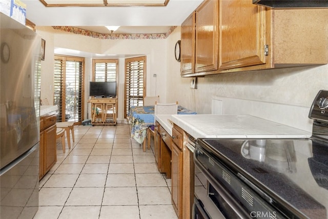 1313 Valley View Rd Unit 202, Glendale, CA 91202 - kitchen with freestanding refrigerator, range with electric stovetop, light tile patterned flooring, brown cabinets, and ventilation hood