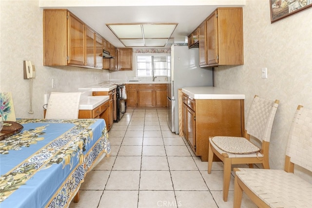 1313 Valley View Rd Unit 202, Glendale, CA 91202 - kitchen featuring light countertops, under cabinet range hood, brown cabinets, freestanding refrigerator, and light tile patterned floors