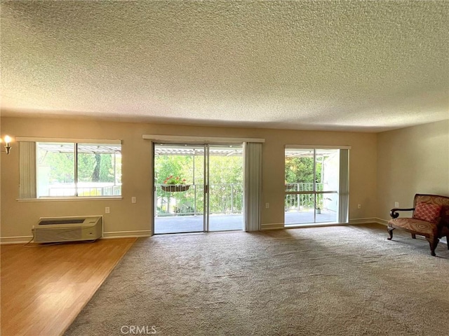 636 NW Avenida Sevilla # O, Laguna Woods, CA 92637 - unfurnished living room featuring a textured ceiling, carpet flooring, a wall unit AC, and a chandelier